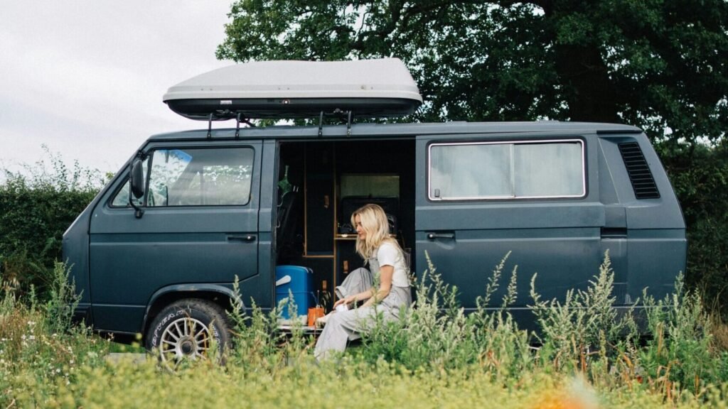 a woman sitting in a van in a field of flowers